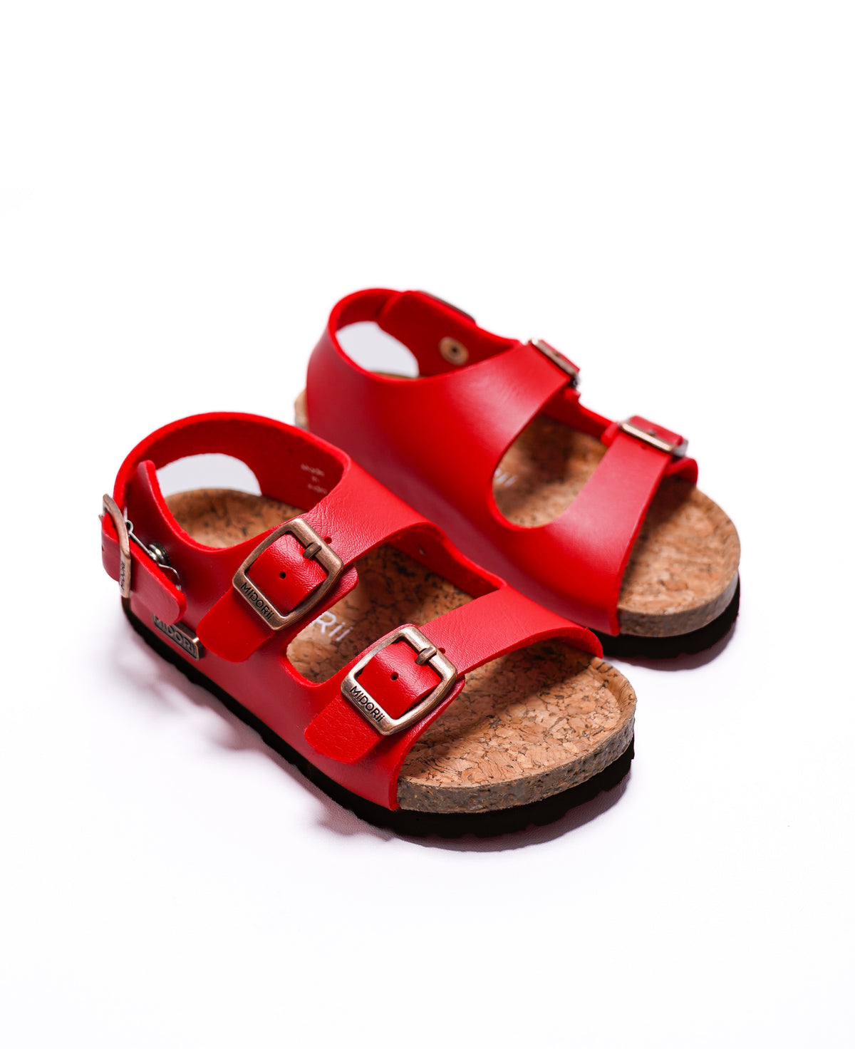 A pair of red leather sandals with double straps and silver buckles, featuring a natural cork footbed and black soles, shown on a white background.