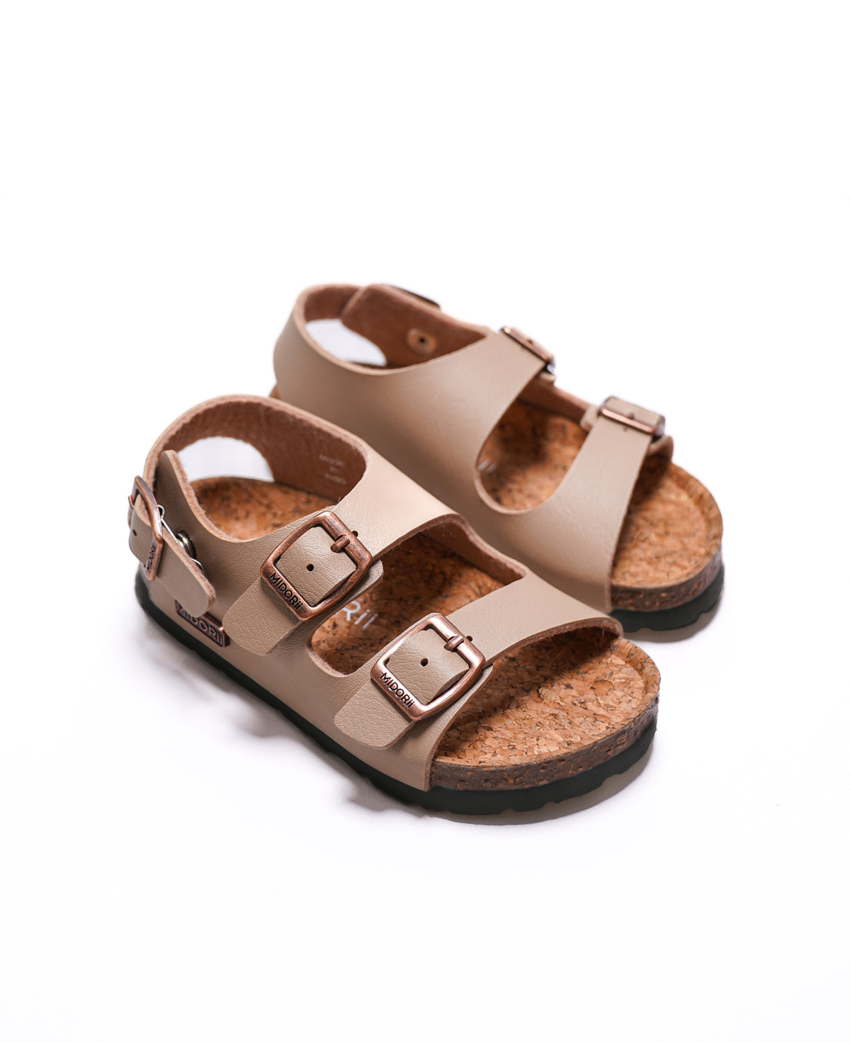 A pair of toddler sandals in beige faux leather with adjustable double straps and metallic buckles, featuring a natural cork footbed and a black outsole, shown on a white background.