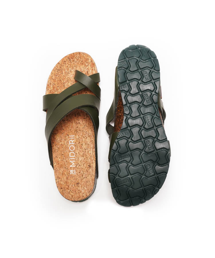Green sandal with cork sole and textured black sole on a white background