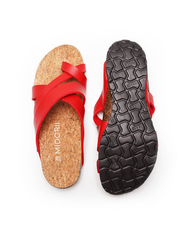 Red sandal with cork sole and textured black sole on a white background